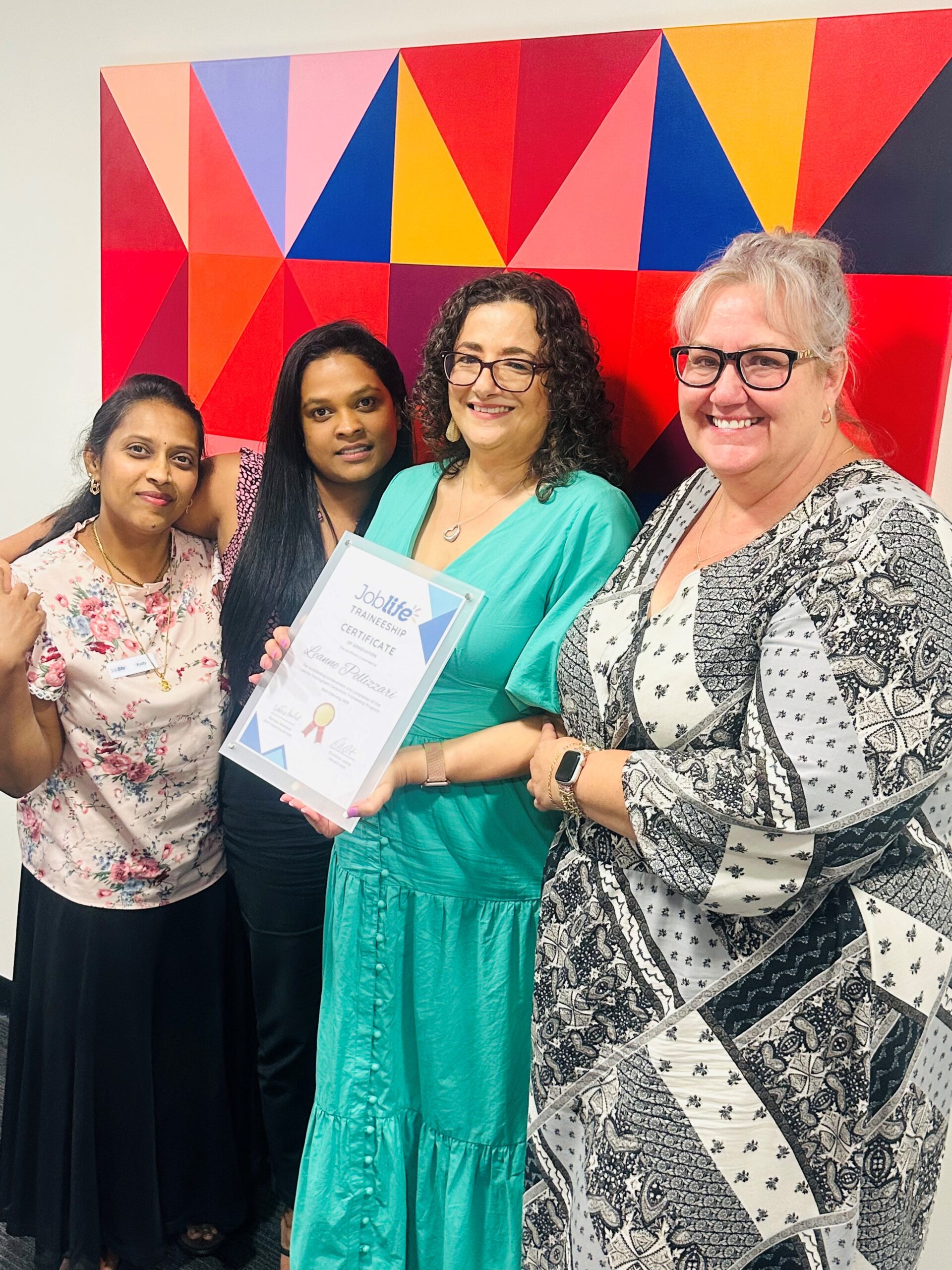 uLaunch - Four women from the traineeship program standing together and smiling - one of the women is holding a certificate.