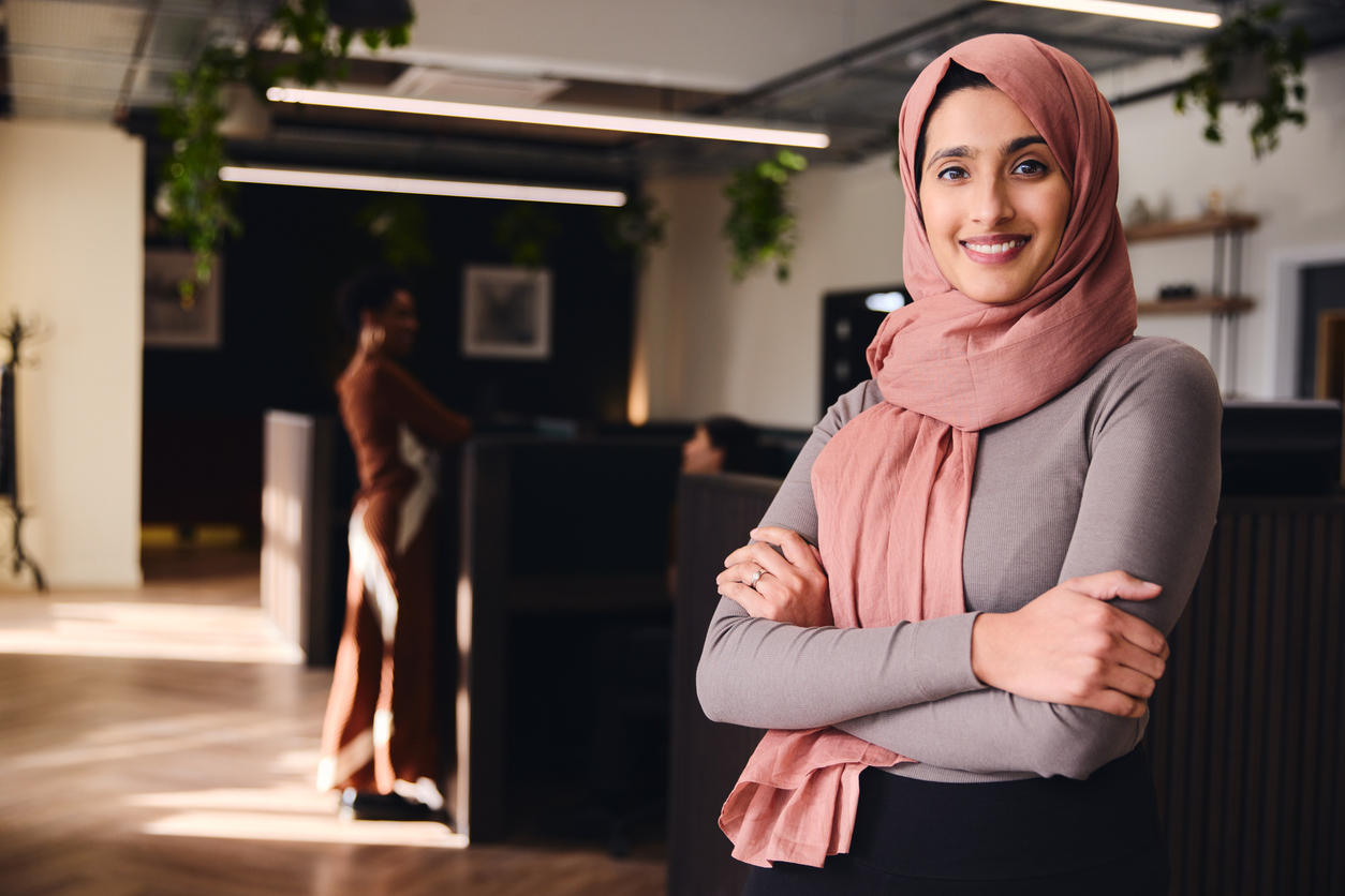 uLaunch - Portrait of confident young Middle Eastern woman smiling and looking at camera in coworking space
